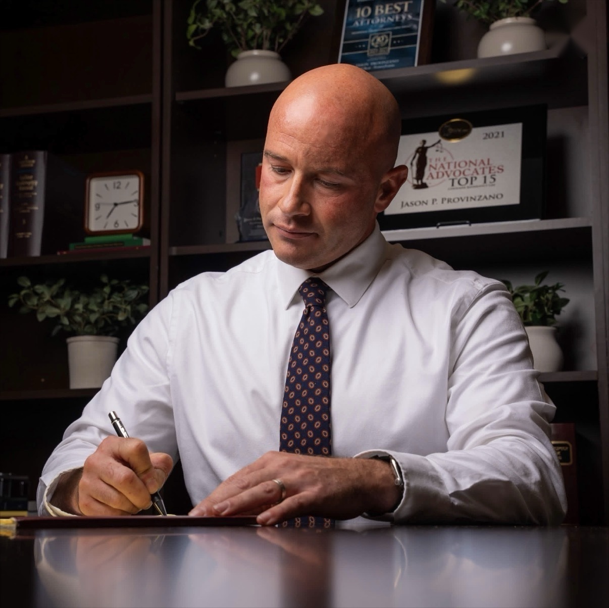 Attorney Jason P. Provinzano signing documents at his desk in his Wilkes-Barre law office